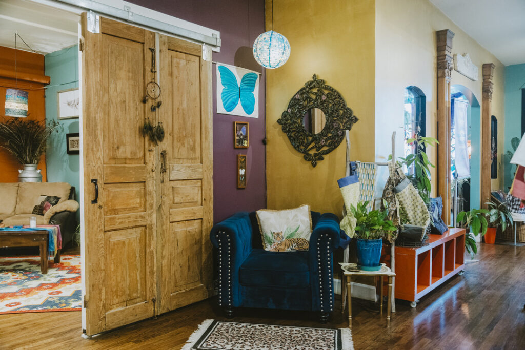 Barn doors to The Shaman & The Mermaid room beside a velvet armchair at Karma Yoga Center