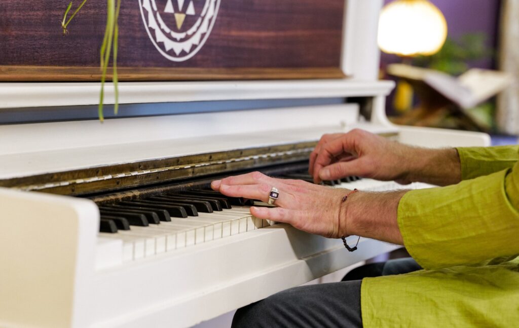 Hands playing the community piano at Karma Yoga Center