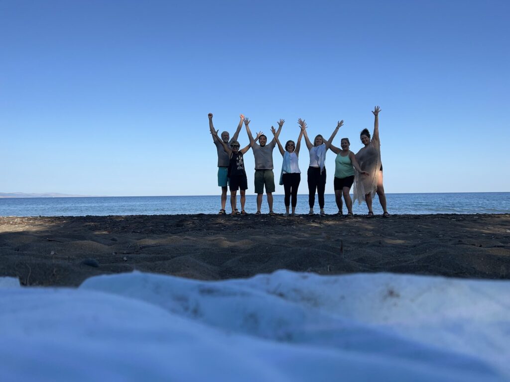 Retreat group with arms raised on a seaside rock in Greece