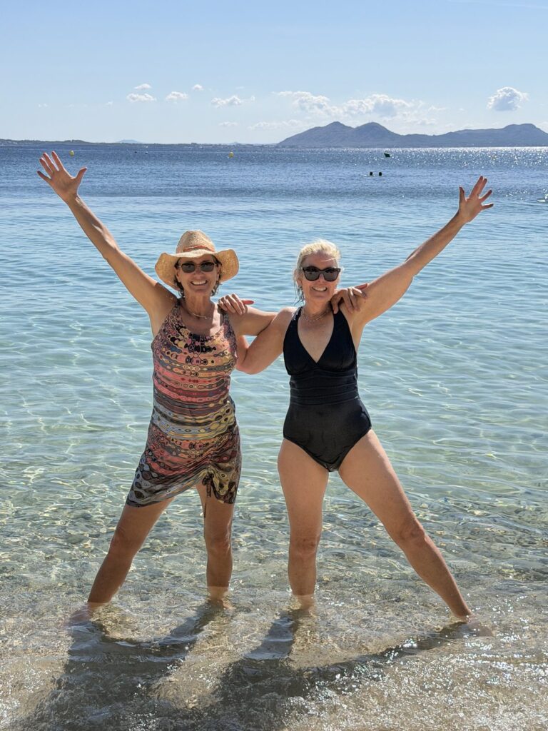 Retreat friends celebrating in the turquoise water at Formentor Beach, Mallorca