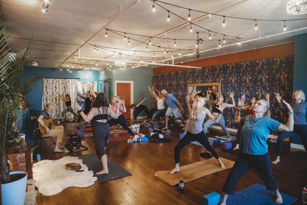 Full yoga class with live guitar music in the main studio at Karma Yoga Center