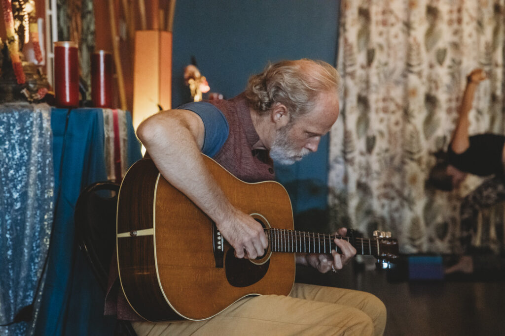 Guitarist playing live music during yoga class at Karma Yoga Center