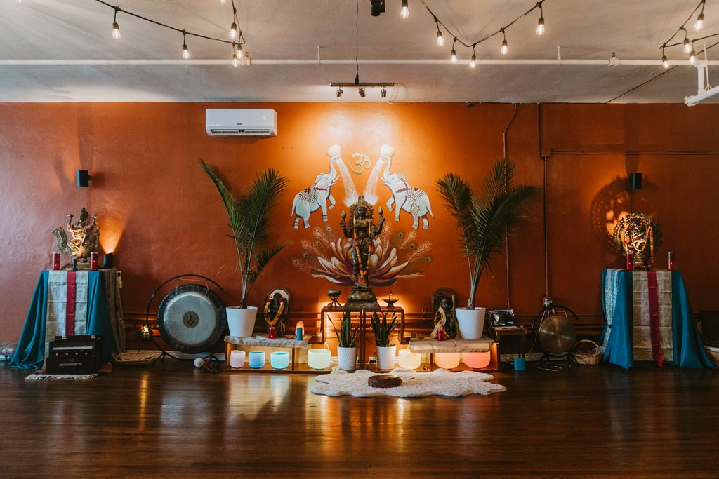 Main yoga studio with altars and string lights at Karma Yoga Center