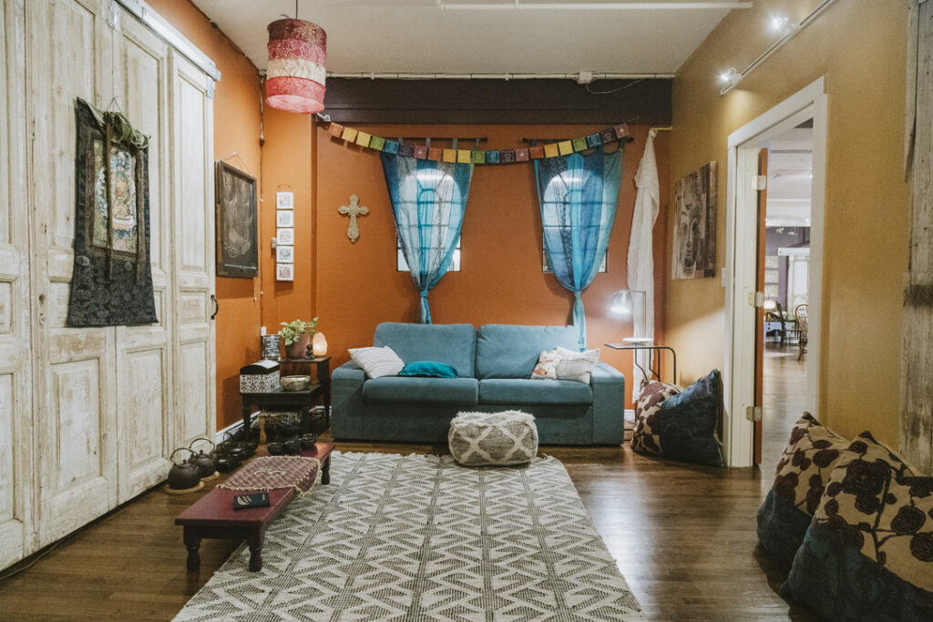 Meditation and tea room with prayer flags and floor cushions at Karma Yoga Center