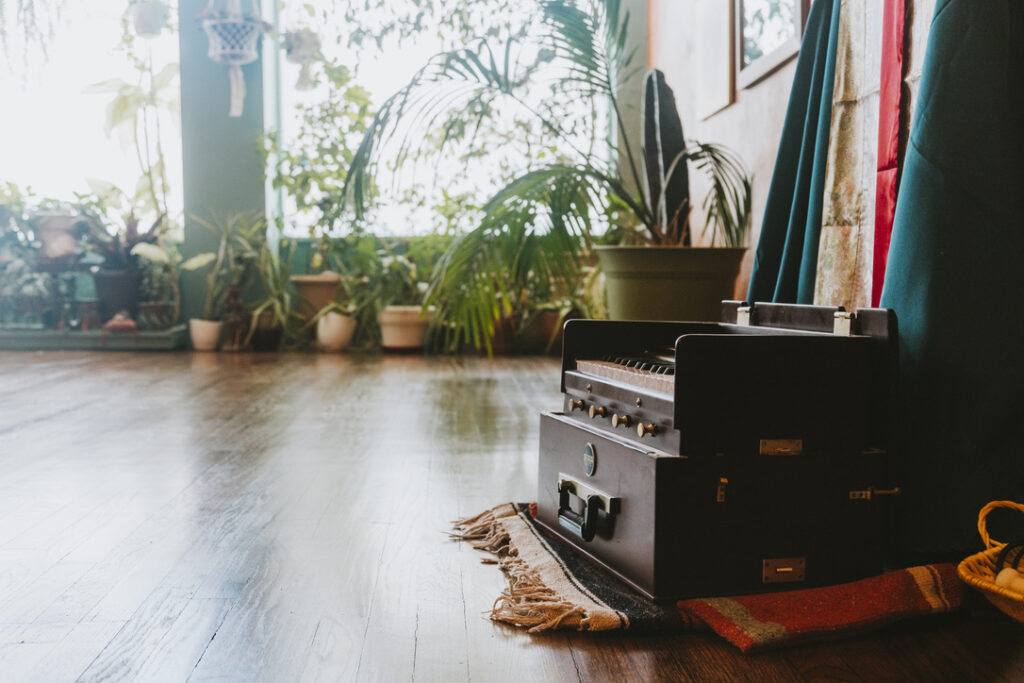 Harmonium by the plant-filled windows in the main studio at Karma Yoga Center