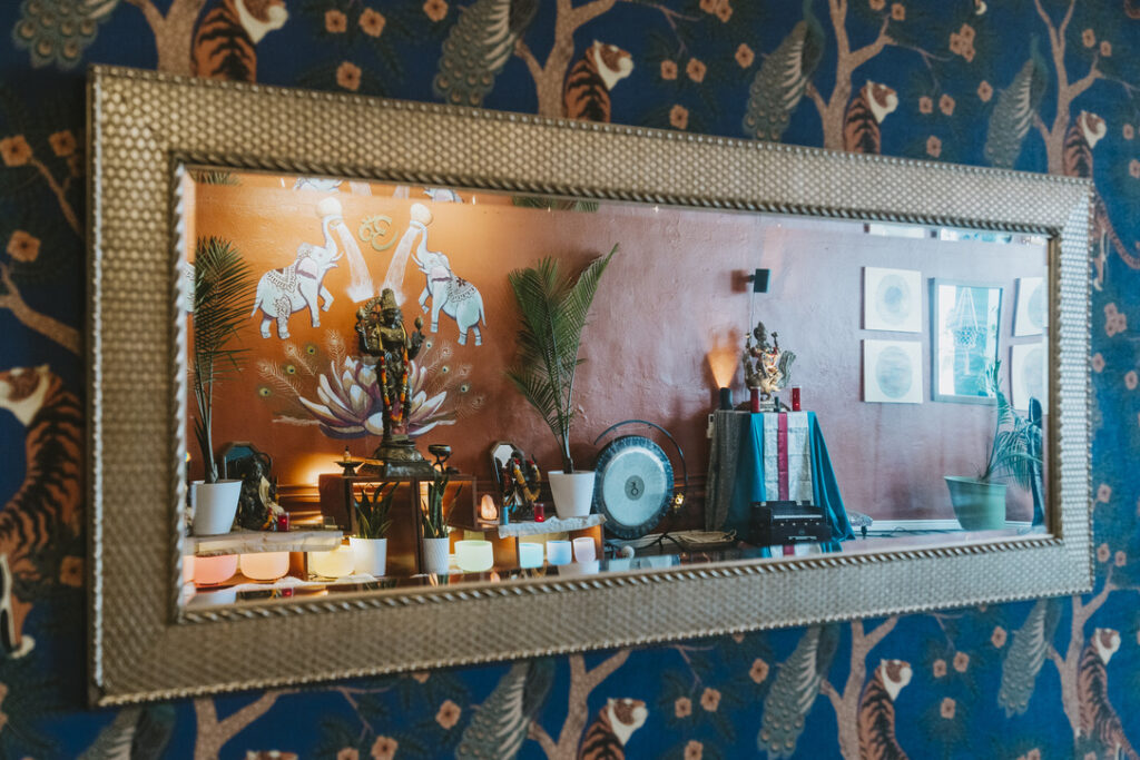 Main studio altar reflected in a mirror on peacock and tiger wallpaper at Karma Yoga Center