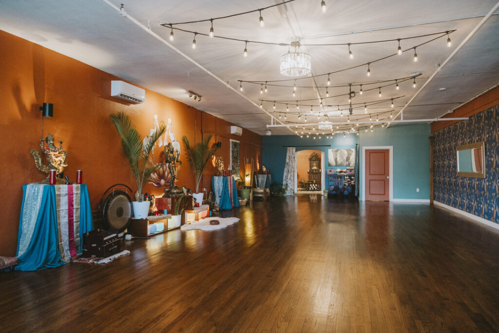 Main yoga studio with string lights and altars at Karma Yoga Center, Denver