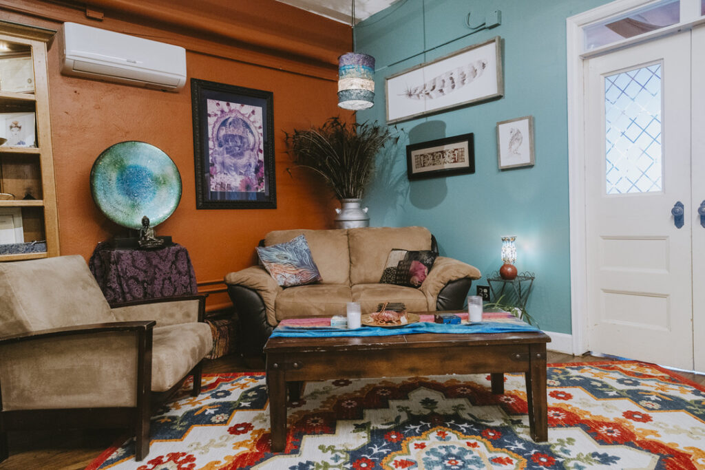 Cozy couch, peacock feathers, and art in The Shaman & The Mermaid room at Karma Yoga Center