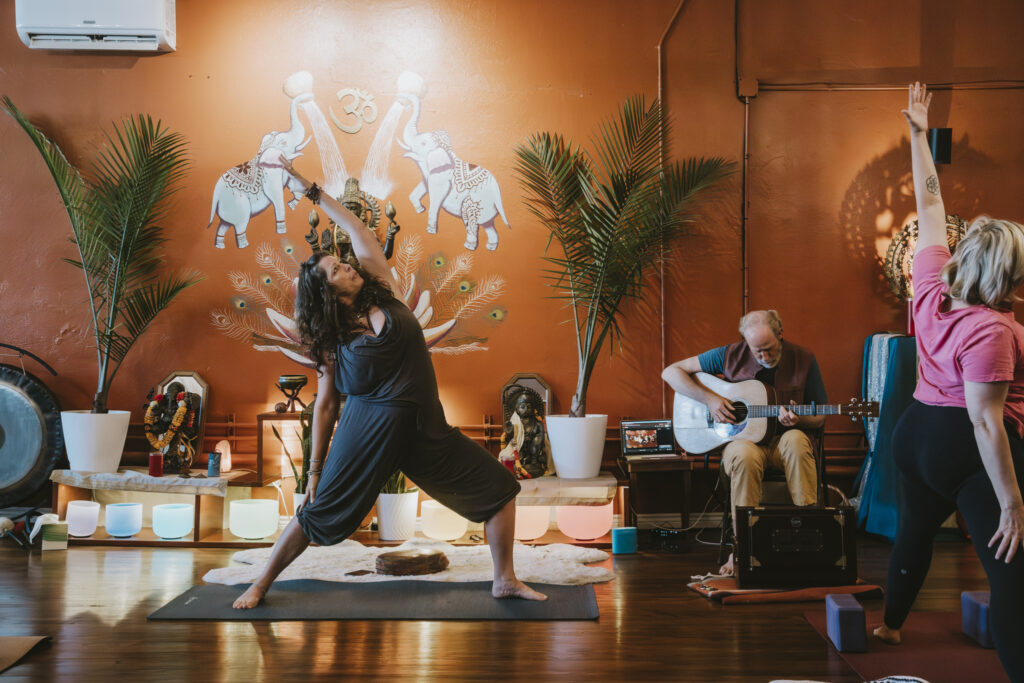 Yoga class with live guitar music in the main studio at Karma Yoga Center