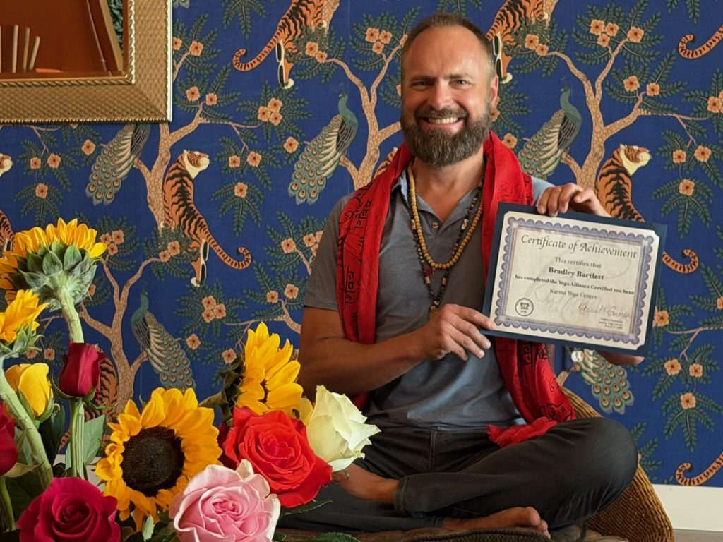 Yoga teacher training graduate holding his Yoga Alliance certificate