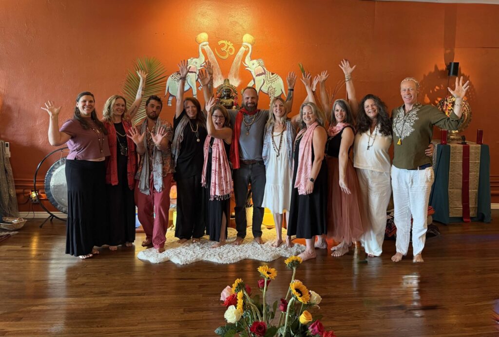 Yoga teacher training graduates celebrating in the main studio at Karma Yoga Center